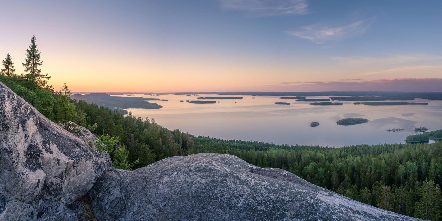 Järvimaisema kalliolta ja taustalla auringonlasku